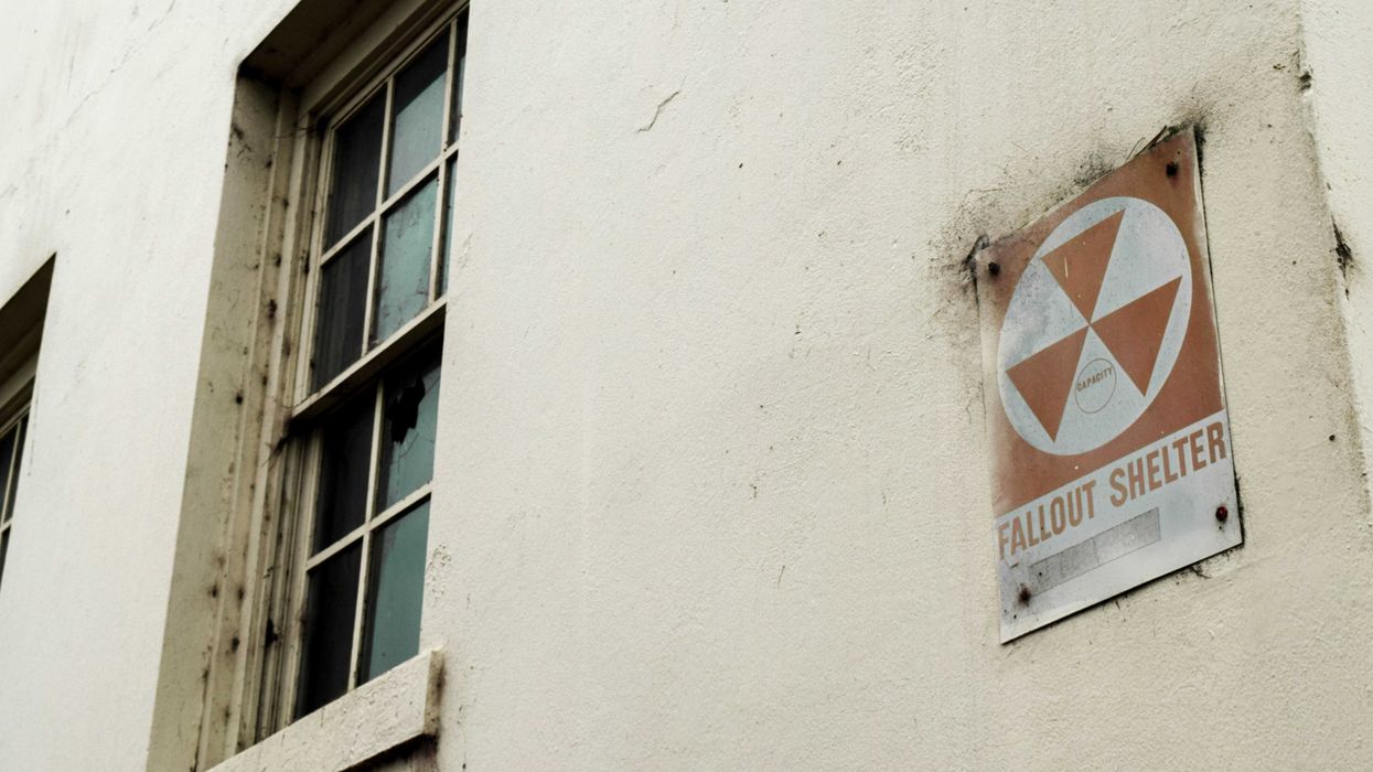 A building with a fallout shelter sign next to a window.