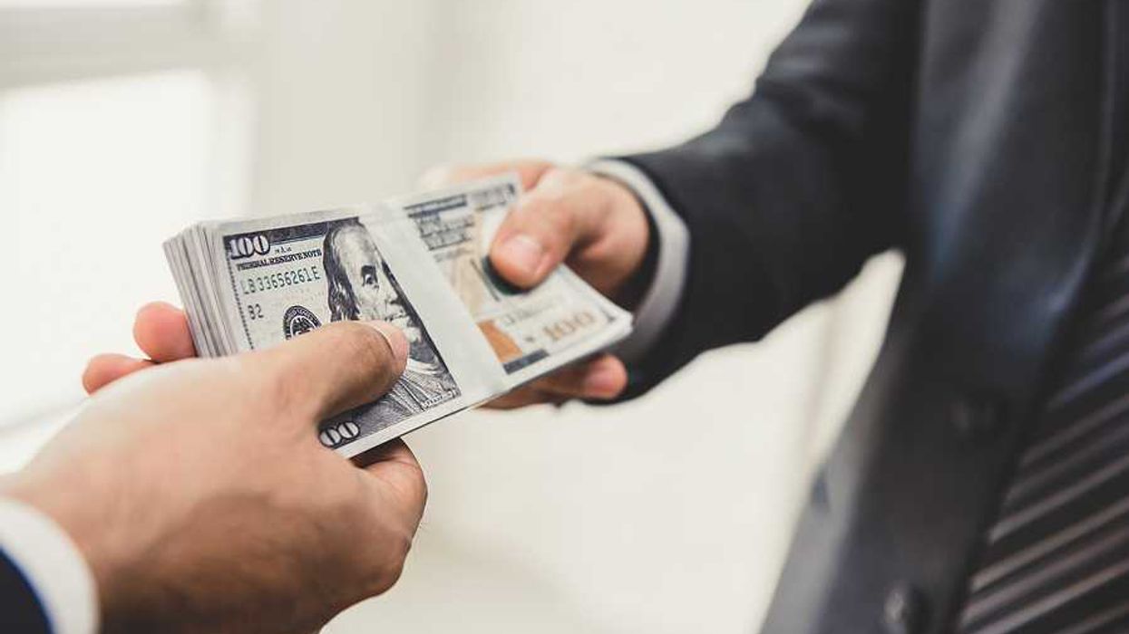 A businessman handing US hundred dollar bill over to another businessman