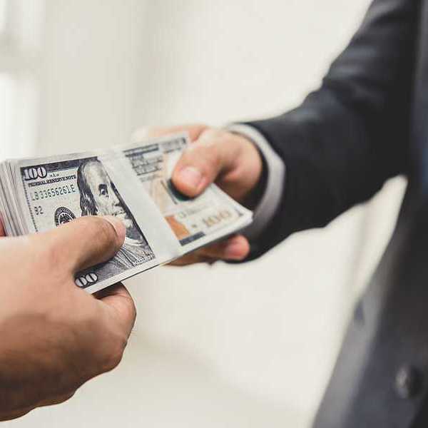A businessman handing US hundred dollar bill over to another businessman