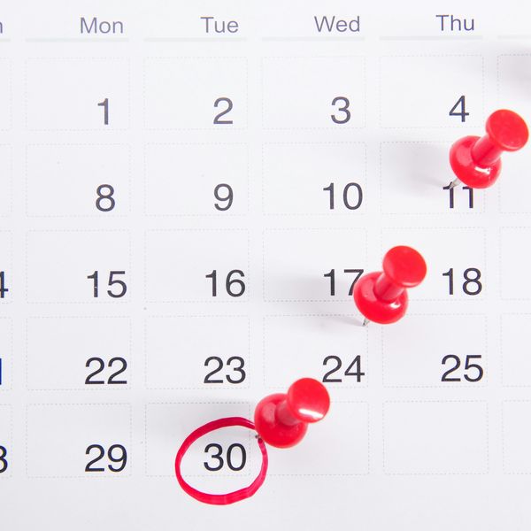 a calendar with red push buttons pinned to it.