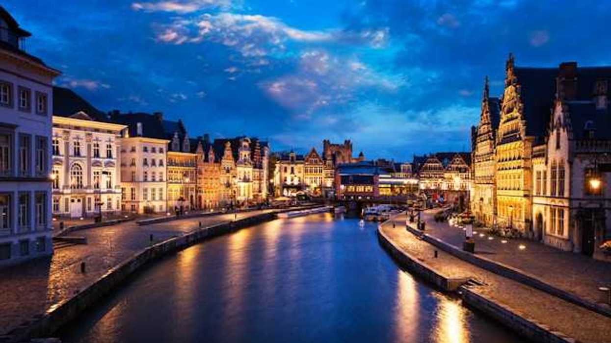 A canal running through Ghent, Belgium with old homes lining the sidewalks