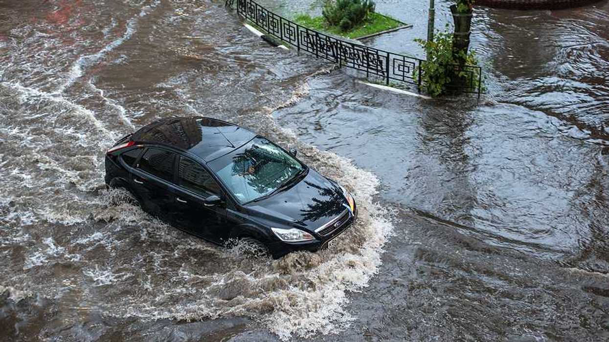 A car driving through floodwaters in a city after a heavy rain