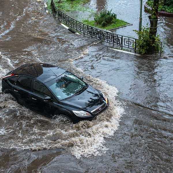 A car driving through floodwaters in a city after a heavy rain
