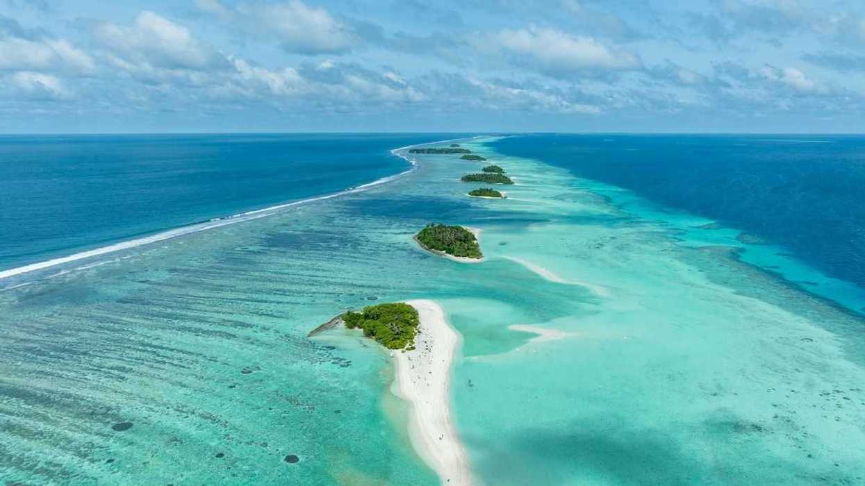 A chain of islands uninhabited in Tha Atoll Maldives. Green islands against turqoise sea.