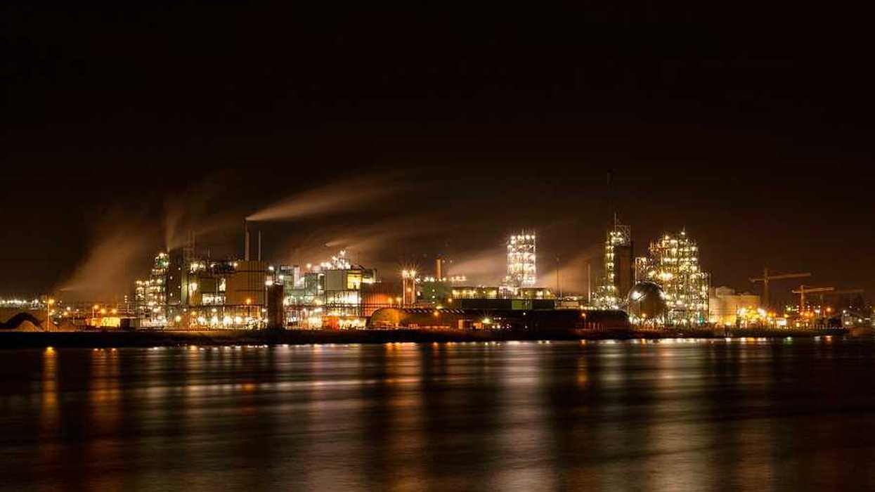 A chemical factory at night lighting up the sky and the water in front of it