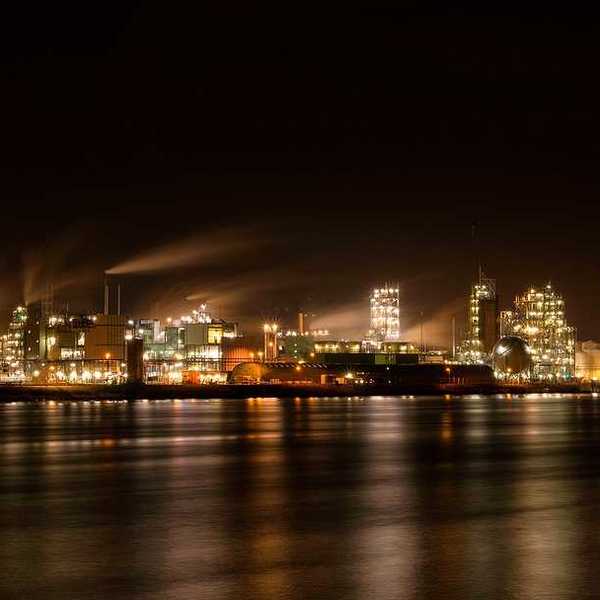 A chemical factory at night lighting up the sky and the water in front of it