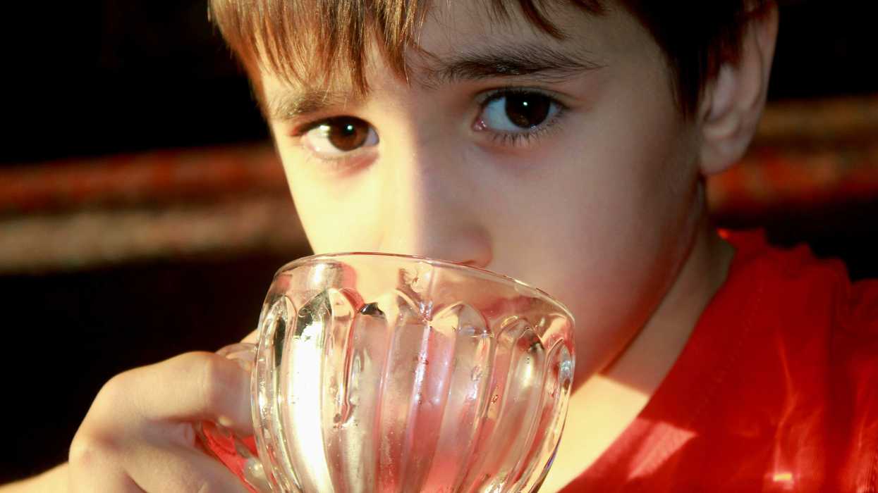 A child drinking water from a glass.