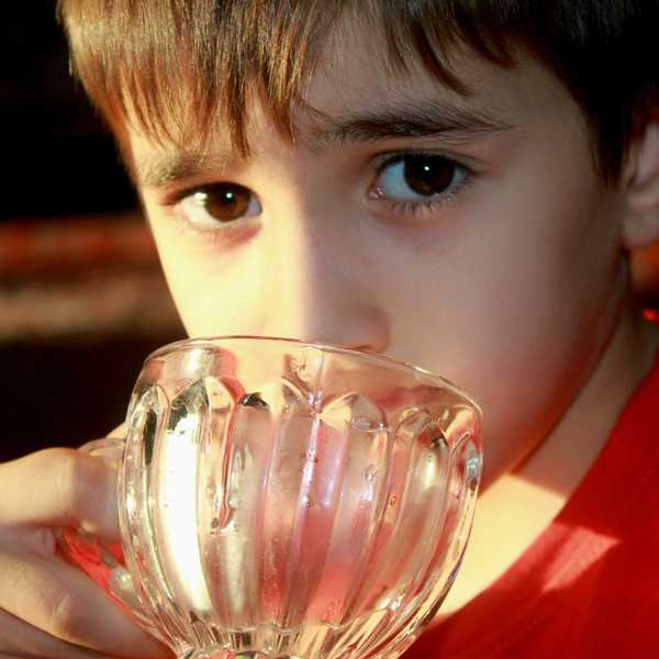 A child drinking water from a glass.