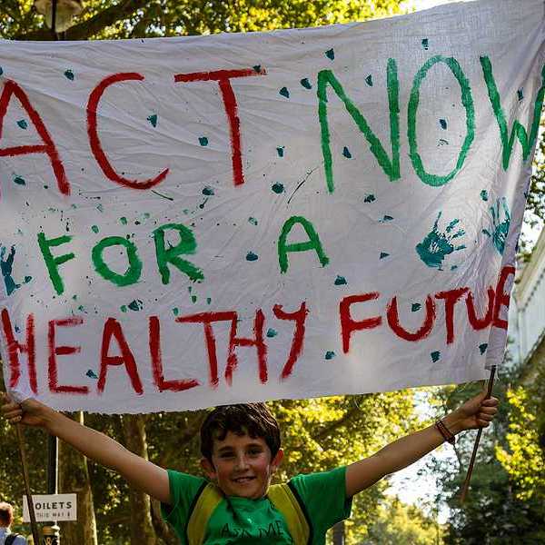 A child holding a protest sign that says Act Now for a Healthy Future