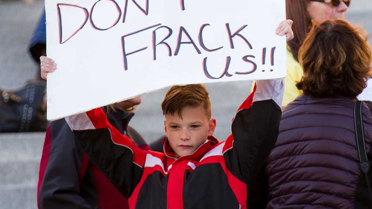 A child holding a protest sign that says Don't Frack Us!!