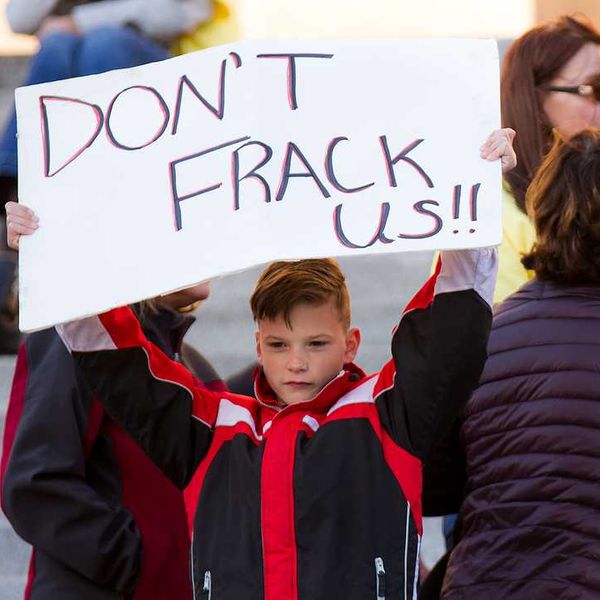 A child holding a protest sign that says Don't Frack Us!!