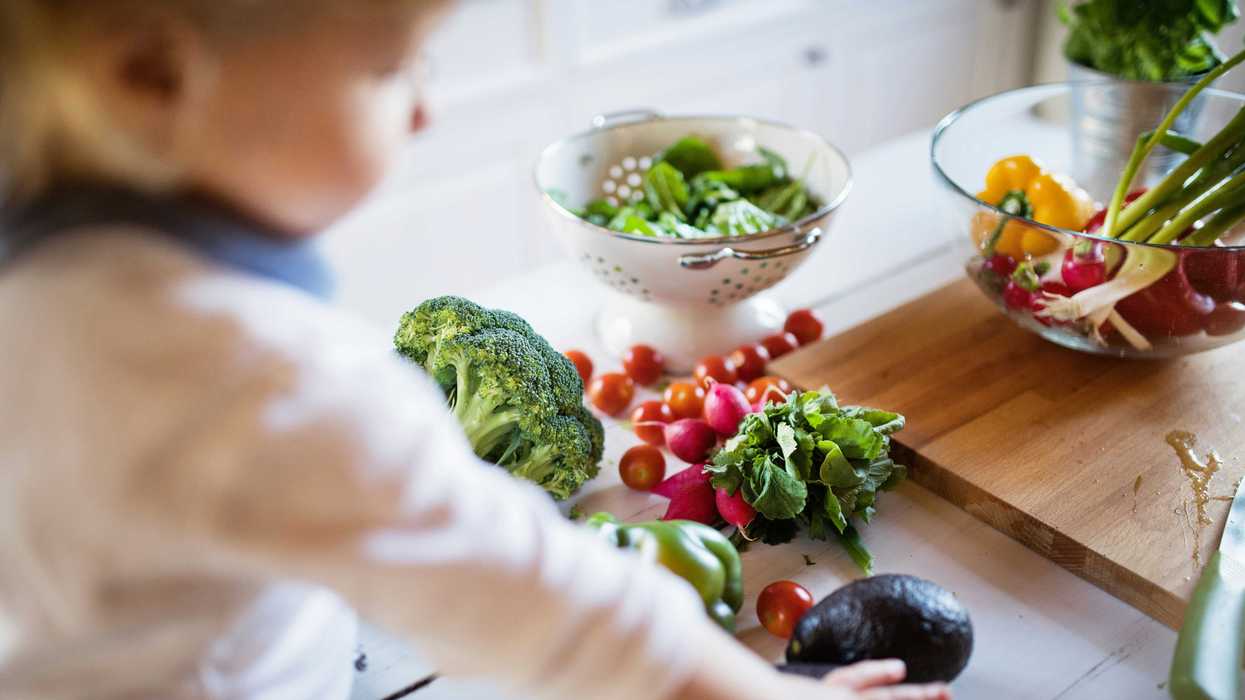 A child reaches for an assortment of vegetables