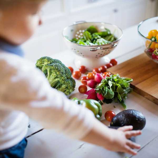 A child reaches for an assortment of vegetables