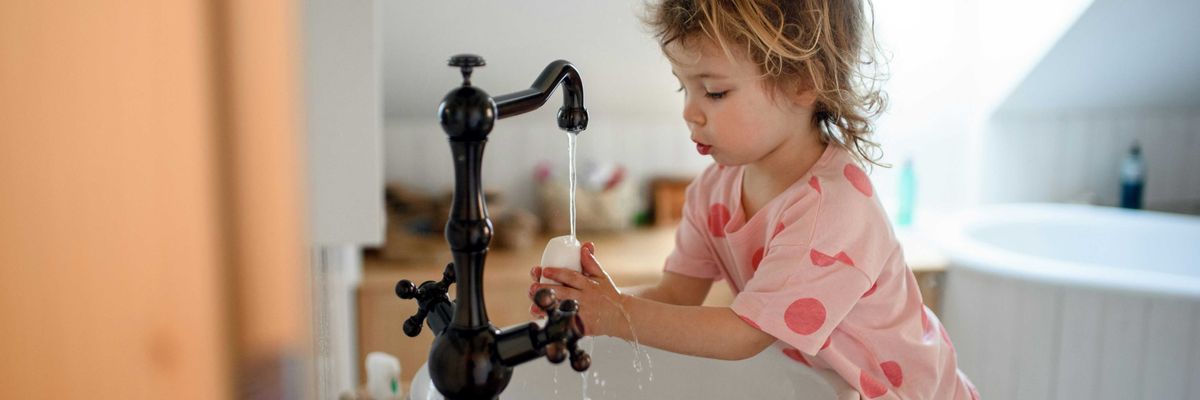 A child runs water out of a faucet