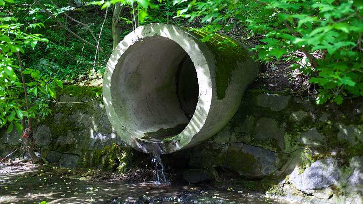 A circular concrete pipe discharging wastewater into waterway