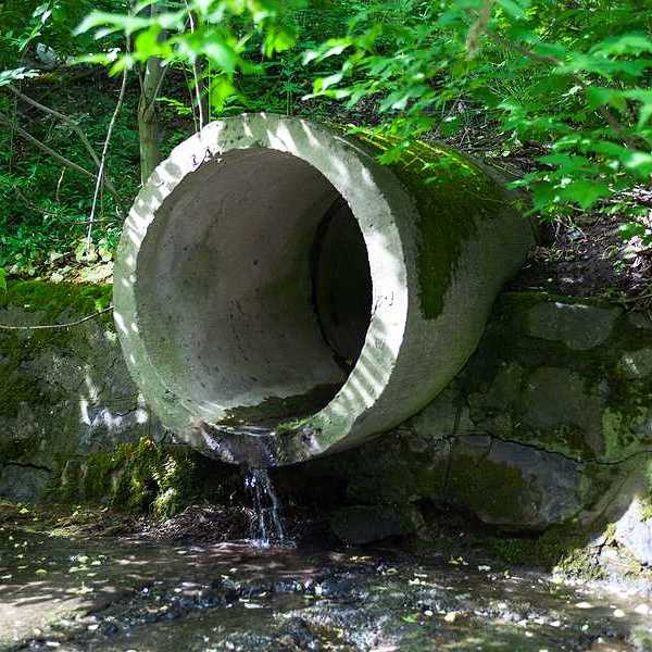 A circular concrete pipe discharging wastewater into waterway