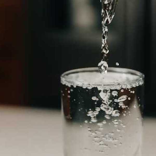 A clear glass being filled with water