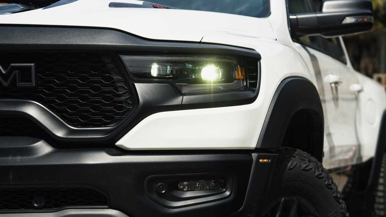 a close up of front of a heavy duty white truck with its lights on.