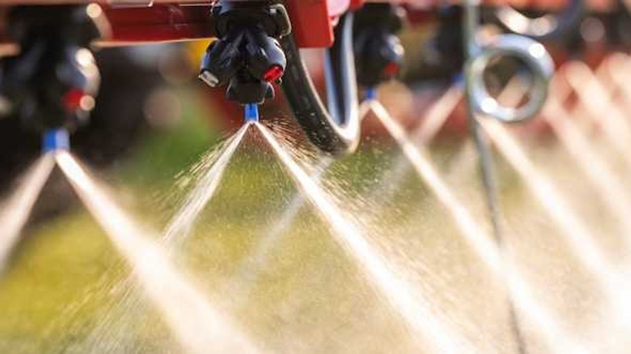 A closeup of a machine spraying pesticides on the ground