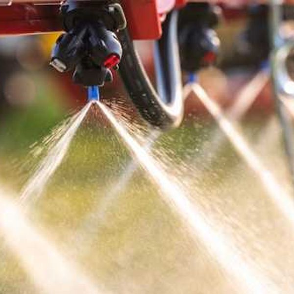 A closeup of a machine spraying pesticides on the ground