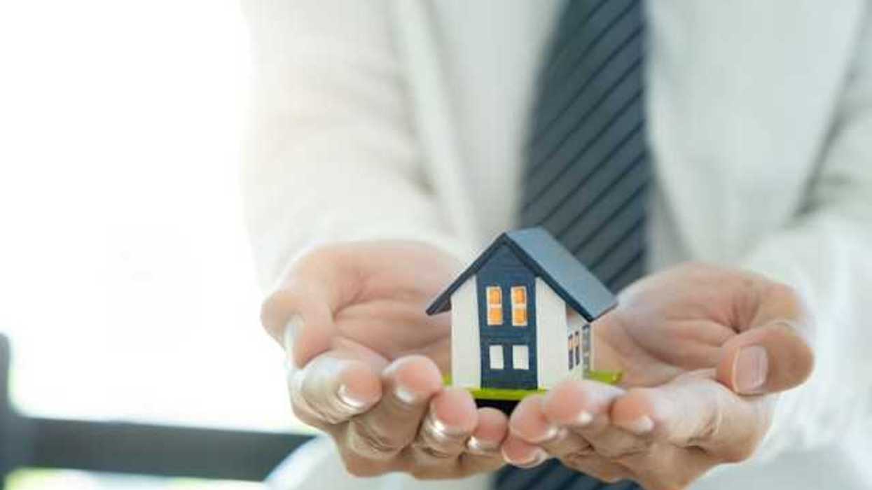A closeup of a person's hands holding a miniature model of a house