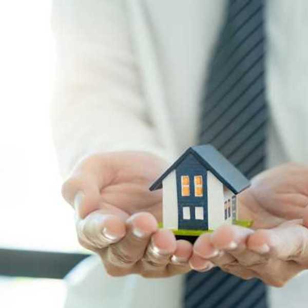 A closeup of a person's hands holding a miniature model of a house