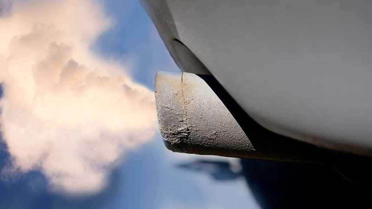 A closeup of a tailpipe with smoke coming out of it
