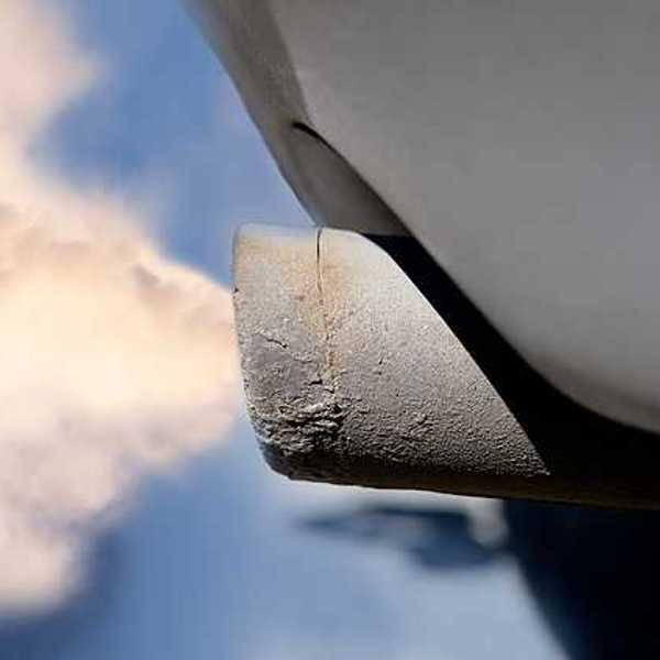 A closeup of a tailpipe with smoke coming out of it