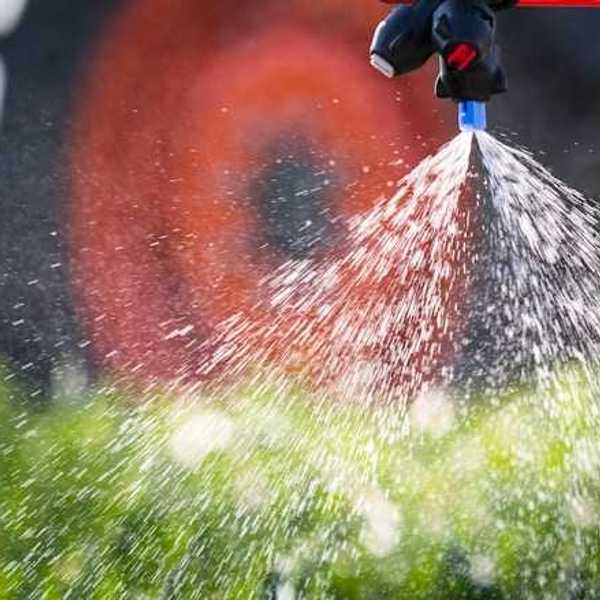 A closeup of a tractor implement spraying pesticides on a field
