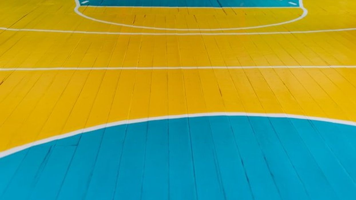 A closeup of a wooden gym floor painted blue and yellow.