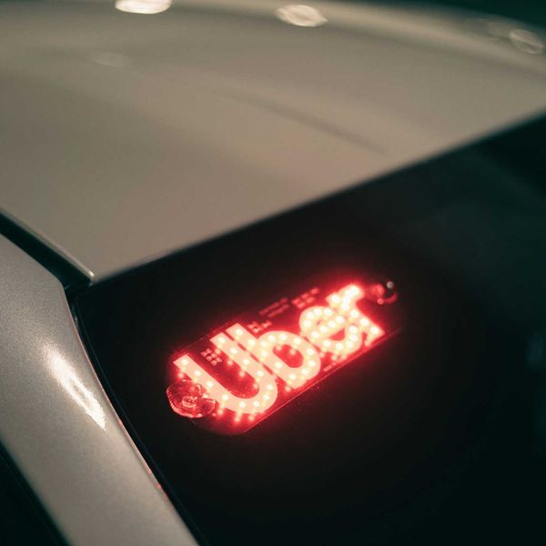 A closeup of an Uber light in the back window of a car