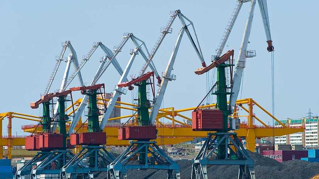 A coal terminal with cranes and piles of coal next to a body of water