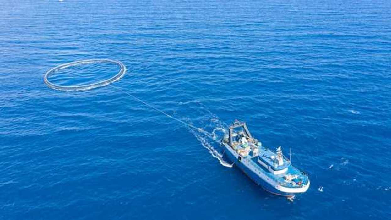 A commercial fishing boat hauling a net behind it in the ocean