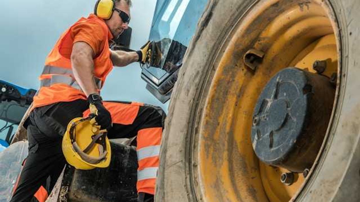 A construction worker climbing into a large piece of machinery