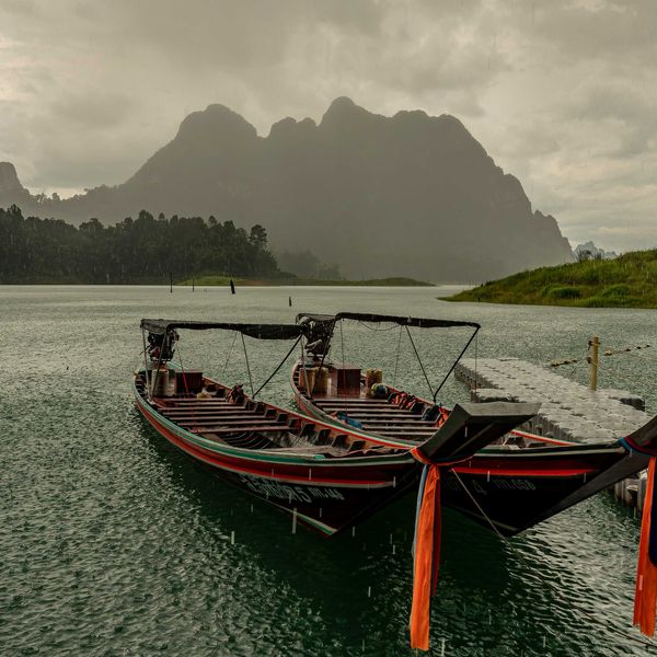 A couple of boats sitting in the water as a storm approaches