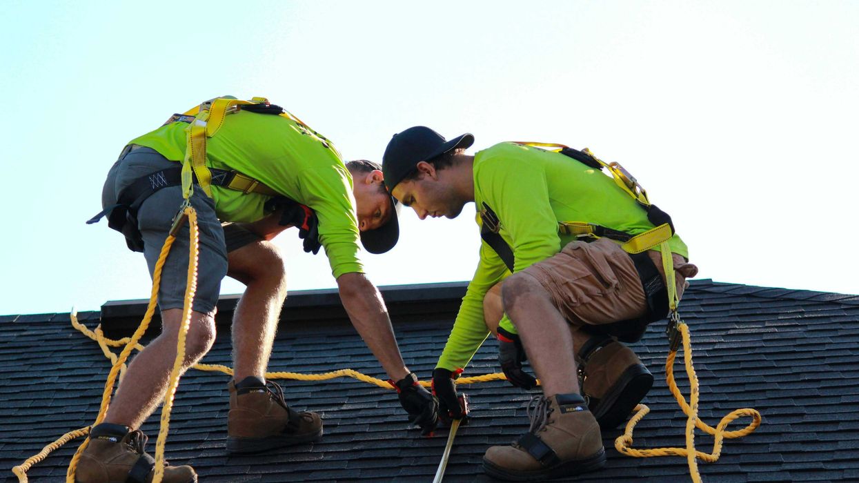 a couple of men working on a roof