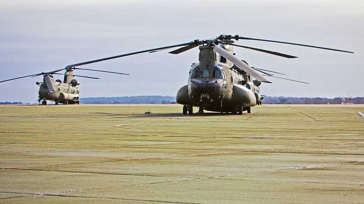 A couple of military helicopters on an air base