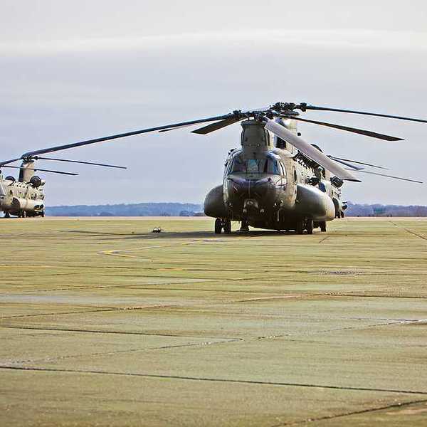 A couple of military helicopters on an air base