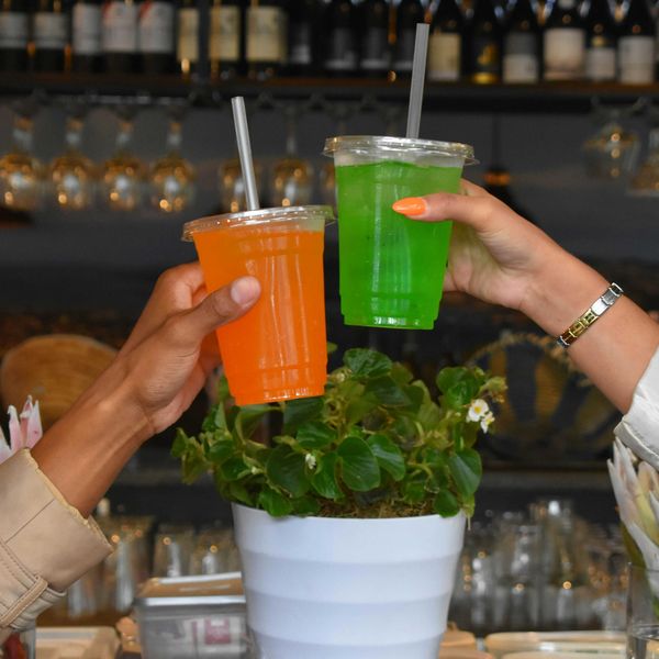 a couple of people holding drinks in plastic containers