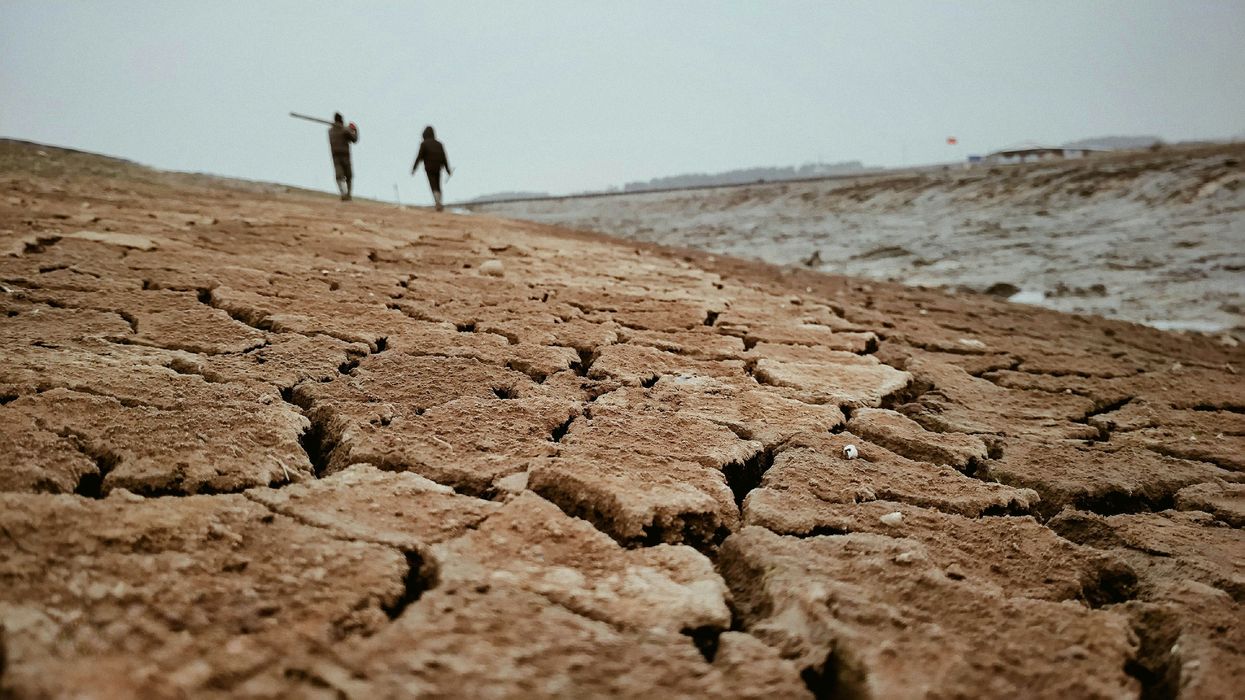 a couple of people walking across a dry field