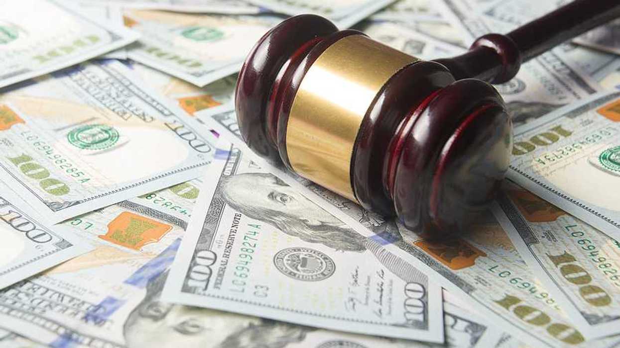 A courtroom gavel on top of piles of $100 bills