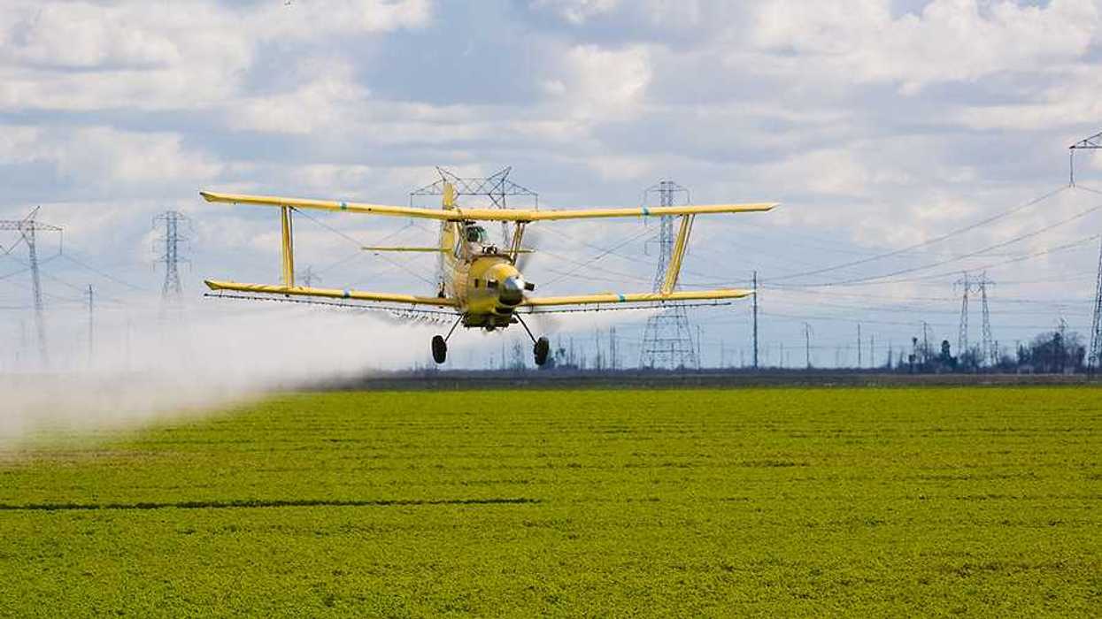 A crop duster spraying pesticides on a farm field