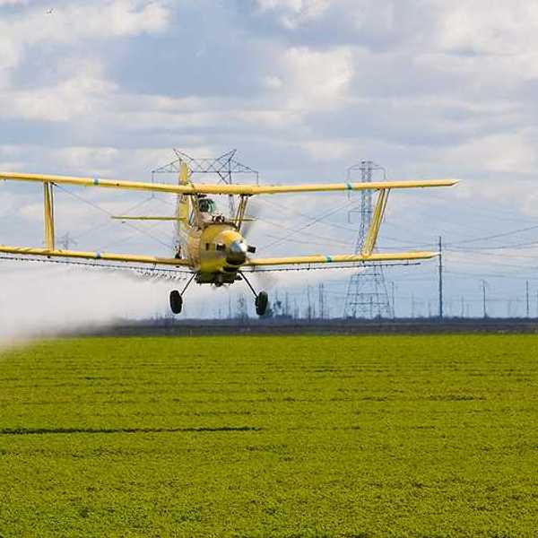 A crop duster spraying pesticides on a farm field