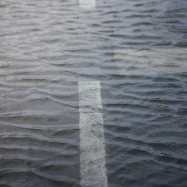 A cross in the road is reflected in a puddle of water