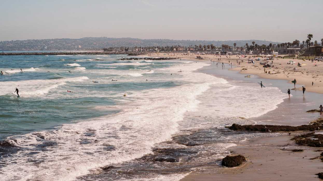 a crowded beach with people swimming in the ocean.
