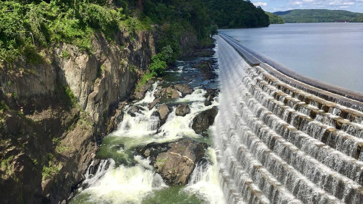 A dam and reservoir with water spilling into a river below.