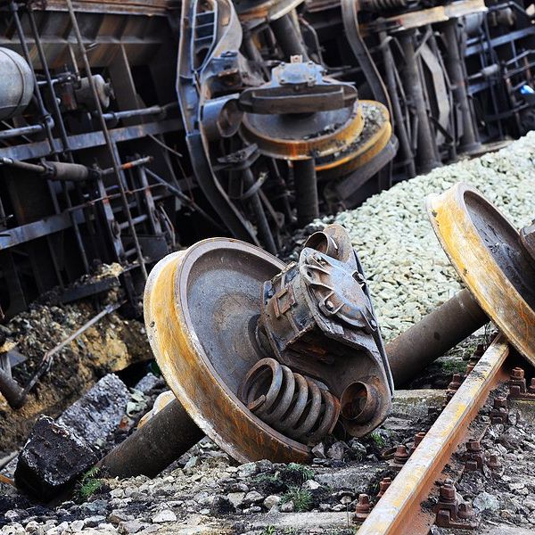 A derailed train on its side with burned wheels