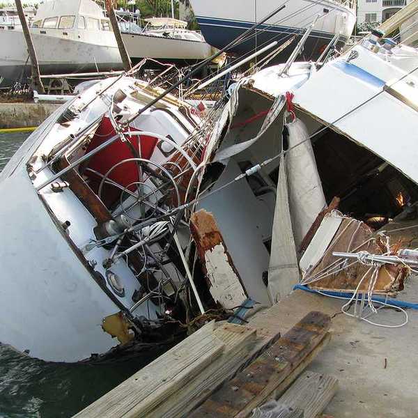 A destroyed boat leaning against a dock after a hurricane