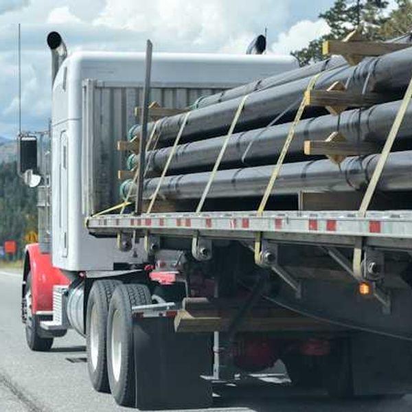 A diesel truck carrying pipeline parts along a highway
