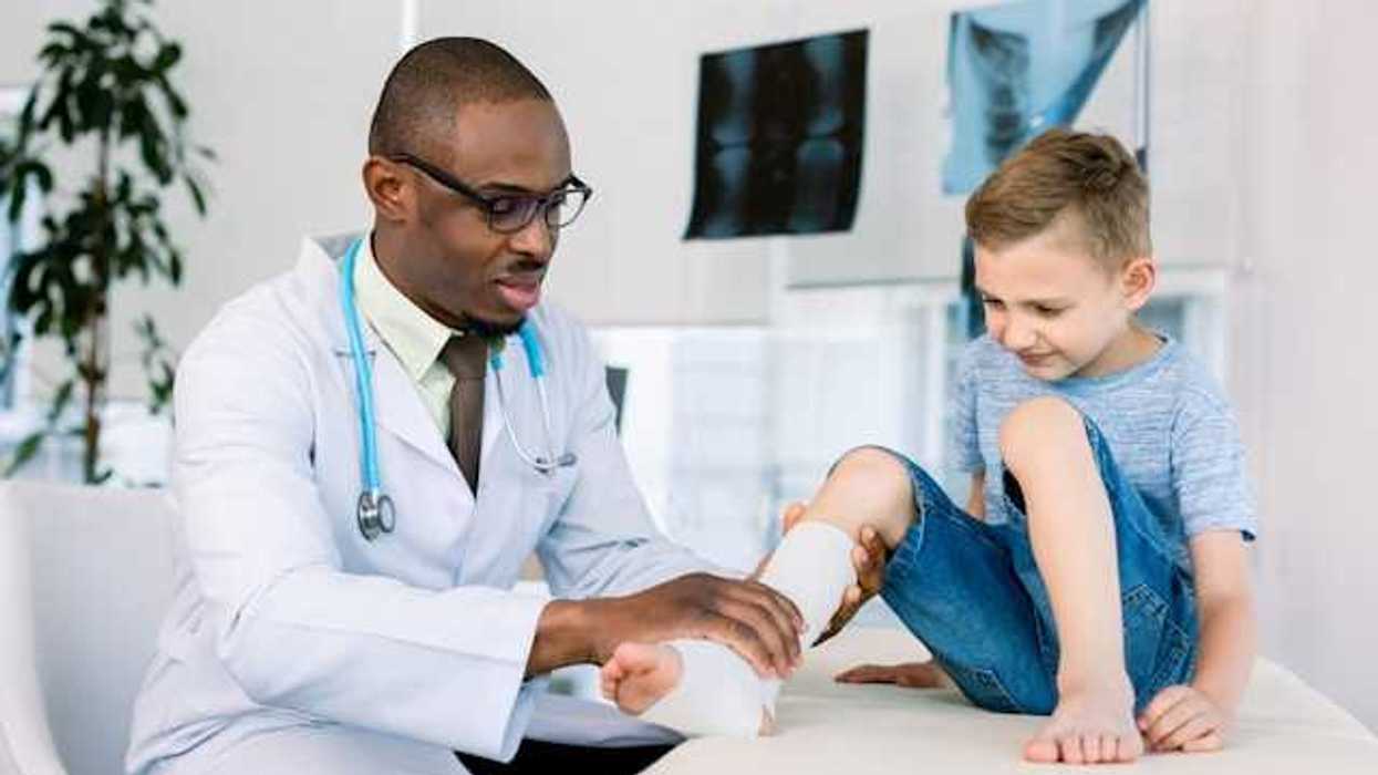 A doctor examining a child's leg which is wrapped in bandages